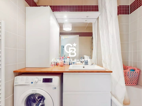 Salle de bain d'un appartement avec machine à laver et lavabo.