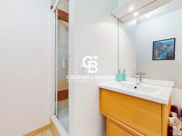 Salle de bain moderne avec lavabo et douche, murs clairs, miroir et décoration simple.