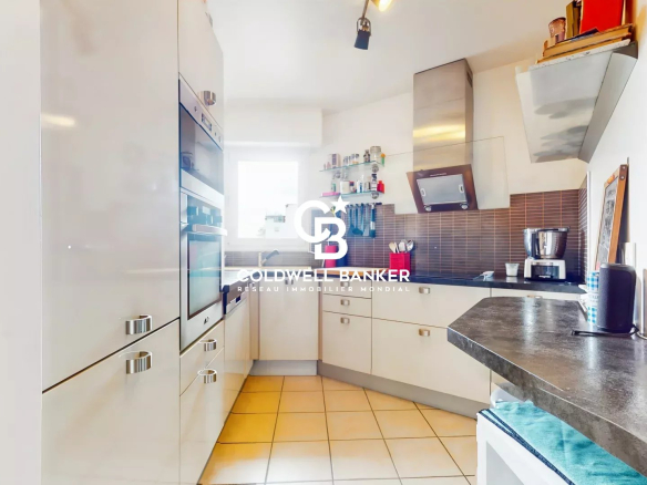 Cuisine moderne d'un appartement à Montrouge, avec des meubles blancs et un plan de travail en noir.