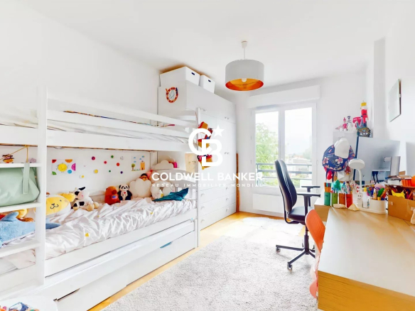 Chambre d'enfant avec lit superposé et bureau, éclairée par une fenêtre.
