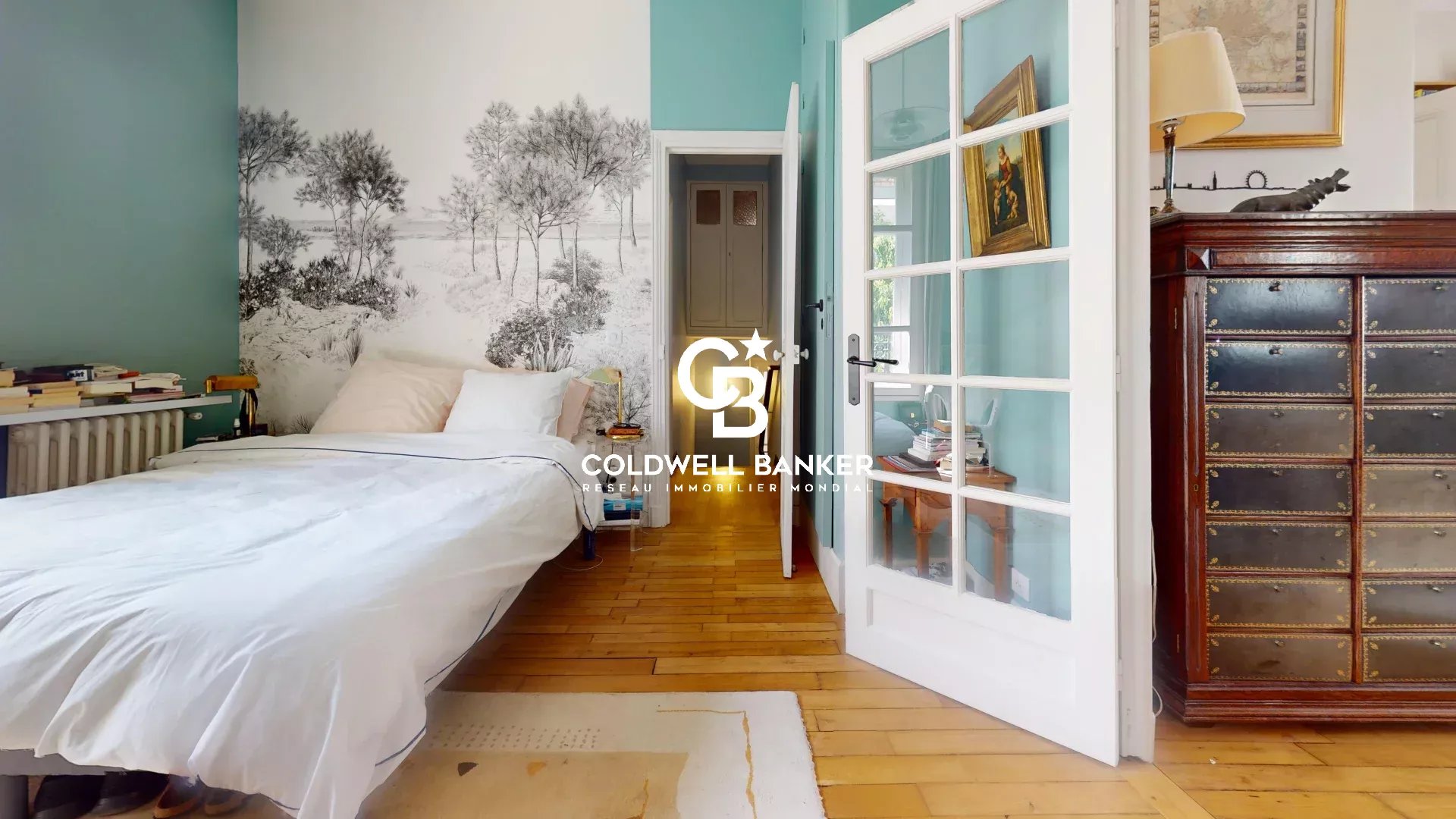 Chambre d'une maison familiale avec murs turquoise et lit, décorée de livres et de meubles en bois.