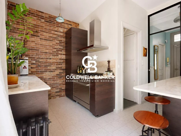 Cuisine moderne avec mur en briques et îlot central dans une maison familiale à Montrouge.