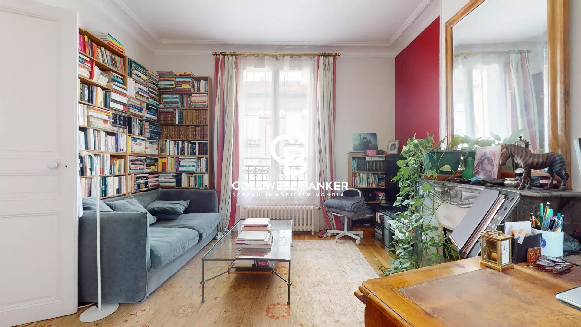 Intérieur d'une maison familiale avec un salon, des étagères remplies de livres et un canapé.