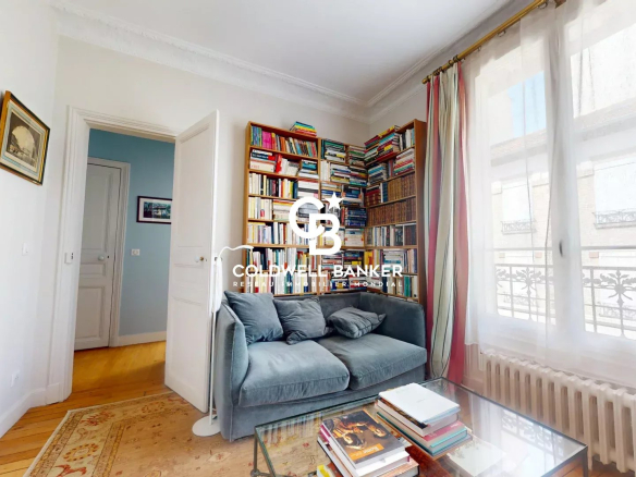 Intérieur d'une maison familiale avec bibliothèque et canapé, lumière naturelle.