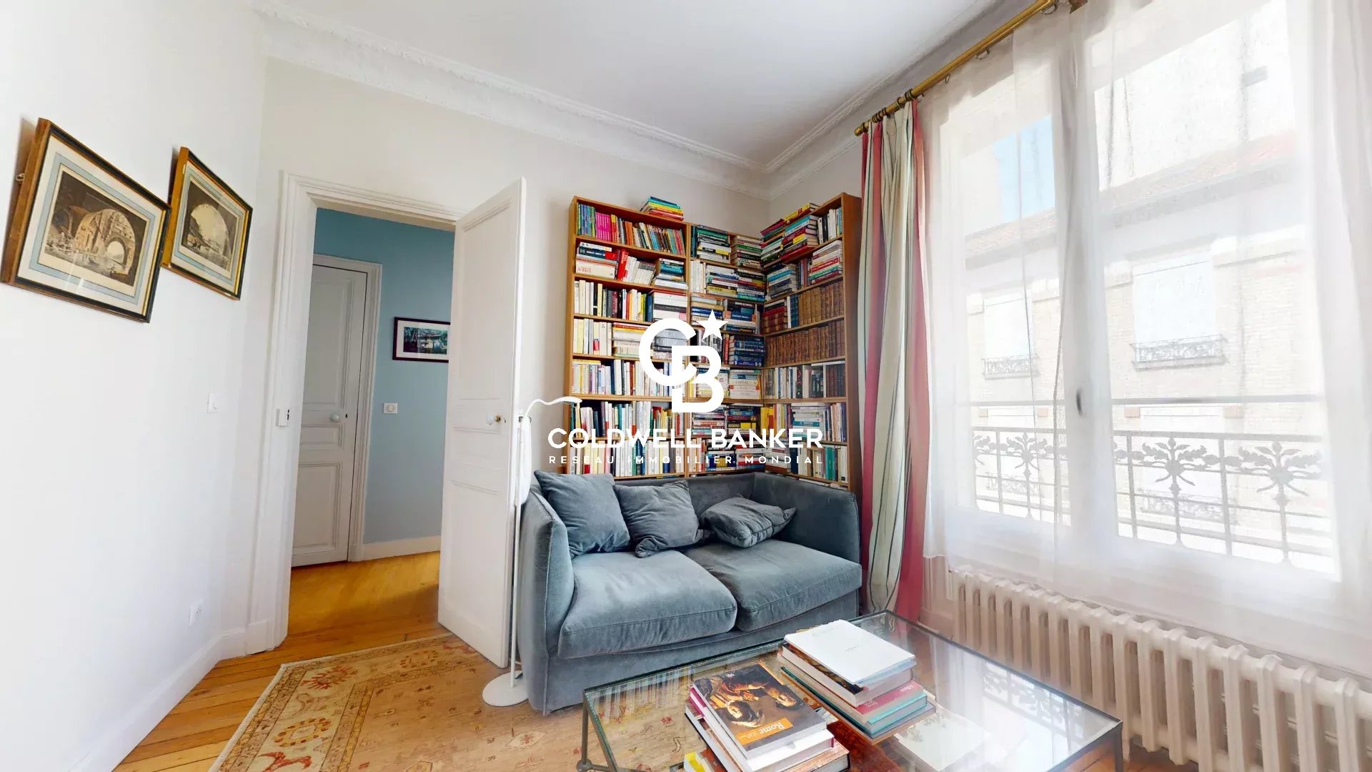 Intérieur d'une maison familiale avec bibliothèque et canapé, lumière naturelle.