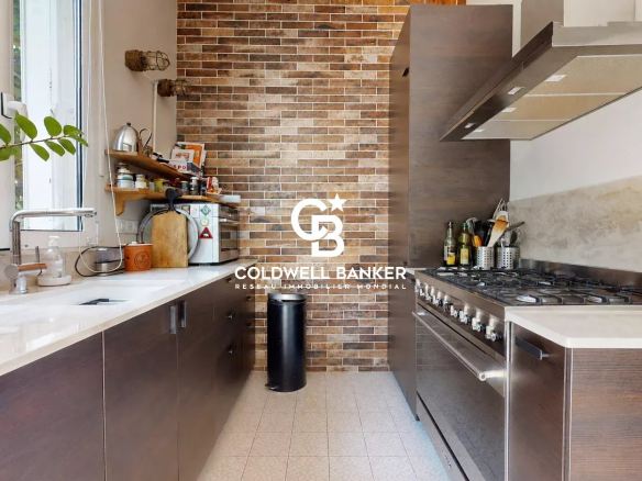 Cuisine moderne avec carrelage et murs en briques, équipée d'un four et d'un évier.