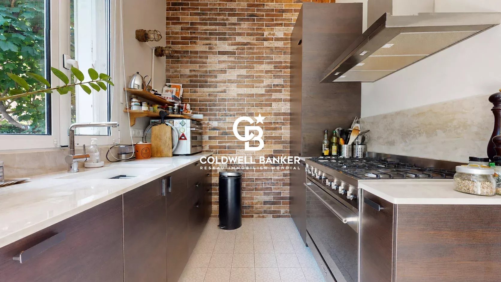 Cuisine moderne avec carrelage et murs en briques, équipée d'un four et d'un évier.