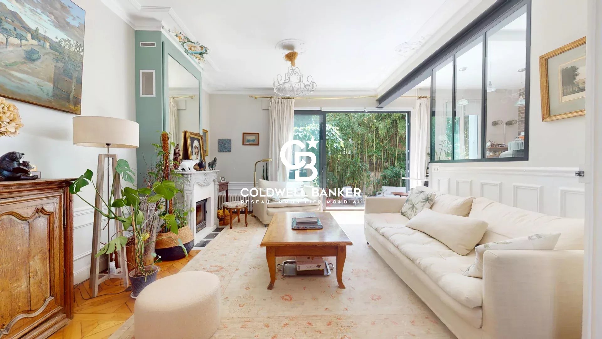Intérieur d'une maison familiale avec salon lumineux et jardin visible à travers de grandes fenêtres.
