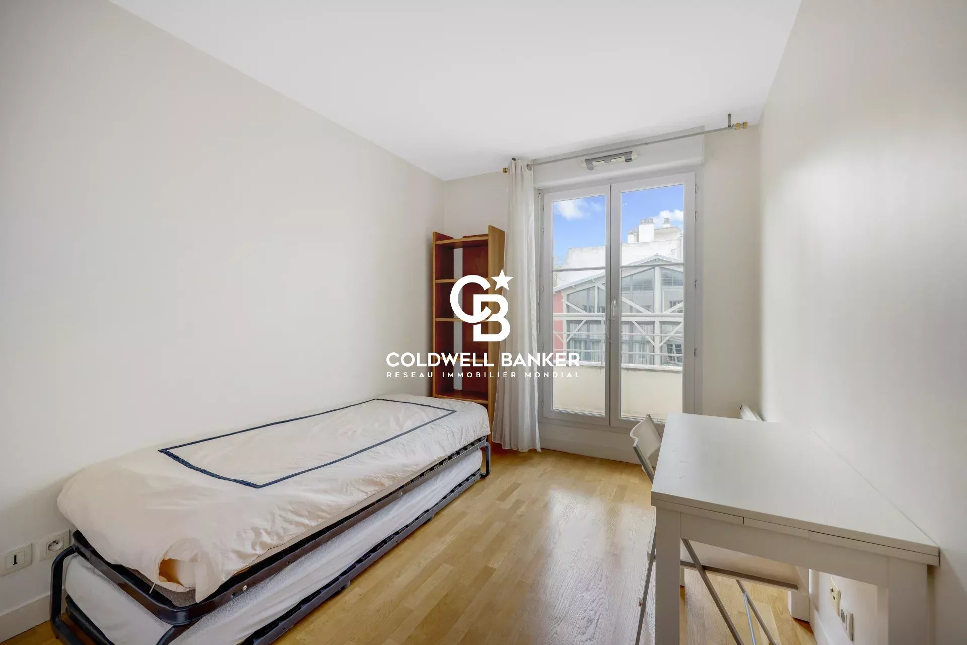Apartment room in Montrouge with bed and desk, window overlooking the outside.