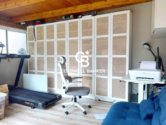 Interior of an apartment with a desk, a sofa and a treadmill.