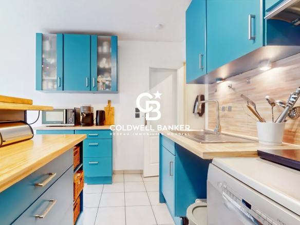 Modern kitchen in an apartment with blue furniture and a wooden worktop.