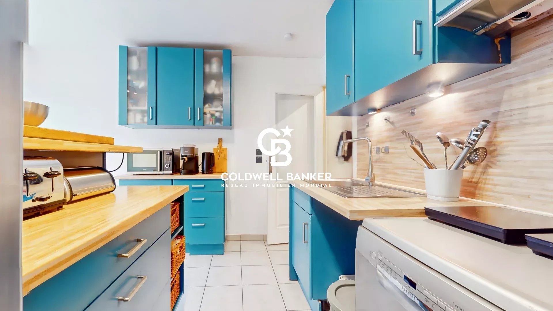 Kitchen of an apartment in Meudon Modern kitchen in an apartment with blue furniture and a wooden worktop.