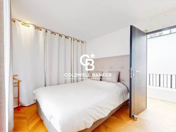 Chambre d'une maison loft industriel à Gentilly avec lit et rideaux clairs.