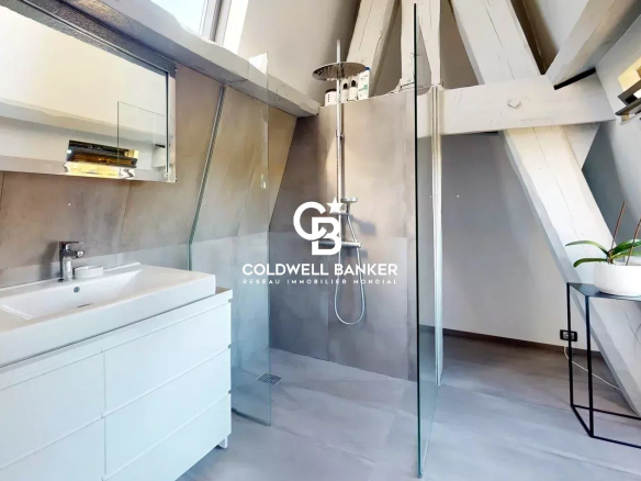 Salle de bain moderne avec douche à l'italienne et lavabo dans un appartement sous les combles.