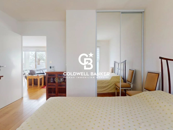 Chambre d'un appartement lumineux avec mobilier en bois et miroir, montrant un espace de vie.