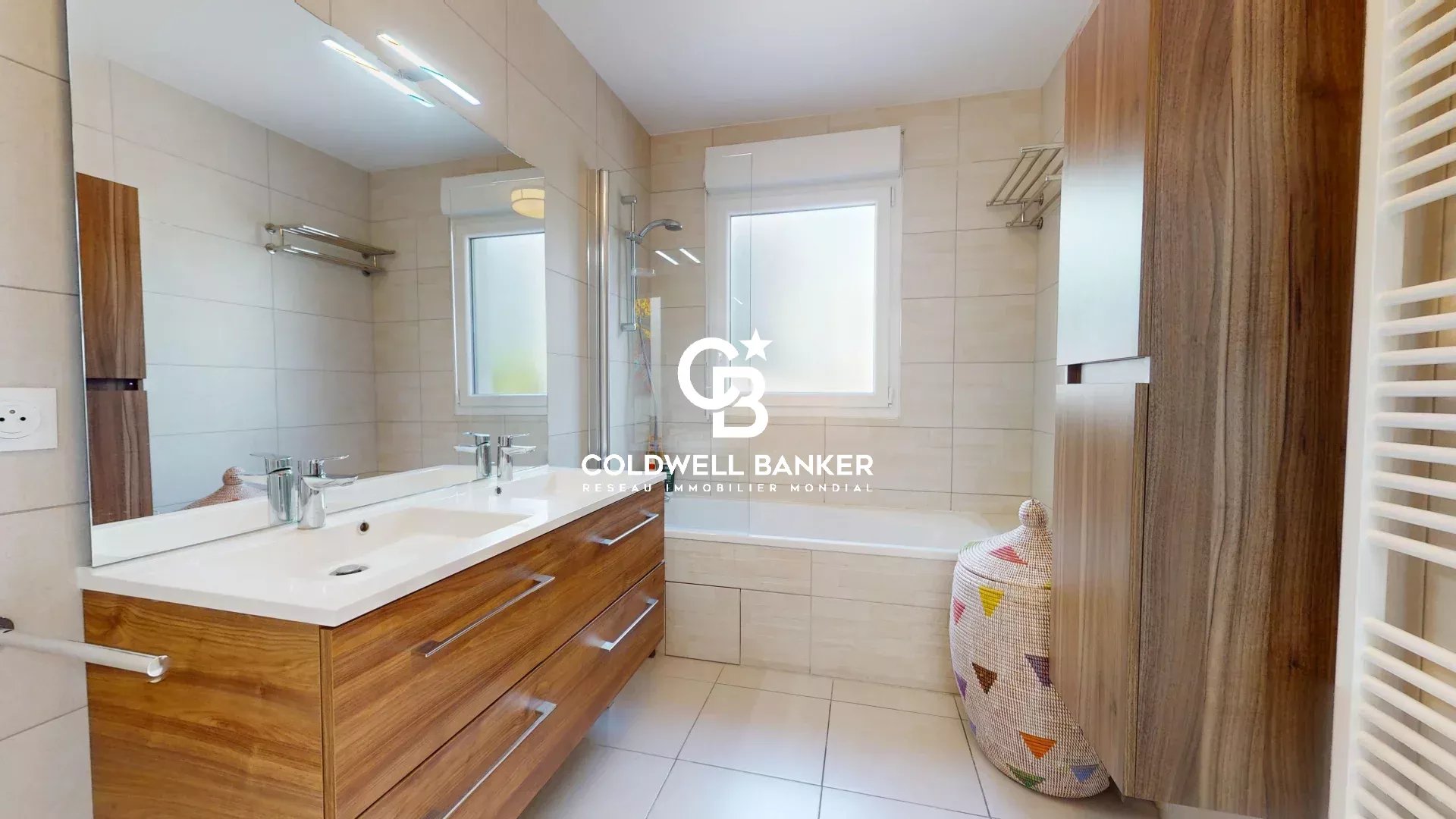 Salle de bain moderne avec meuble en bois et miroir, fenêtres laissant entrer la lumière