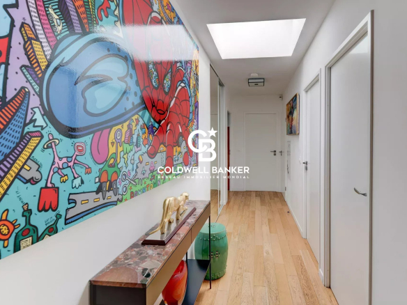 Intérieur d'un appartement moderne avec couloir décoré d'œuvres d'art colorées.