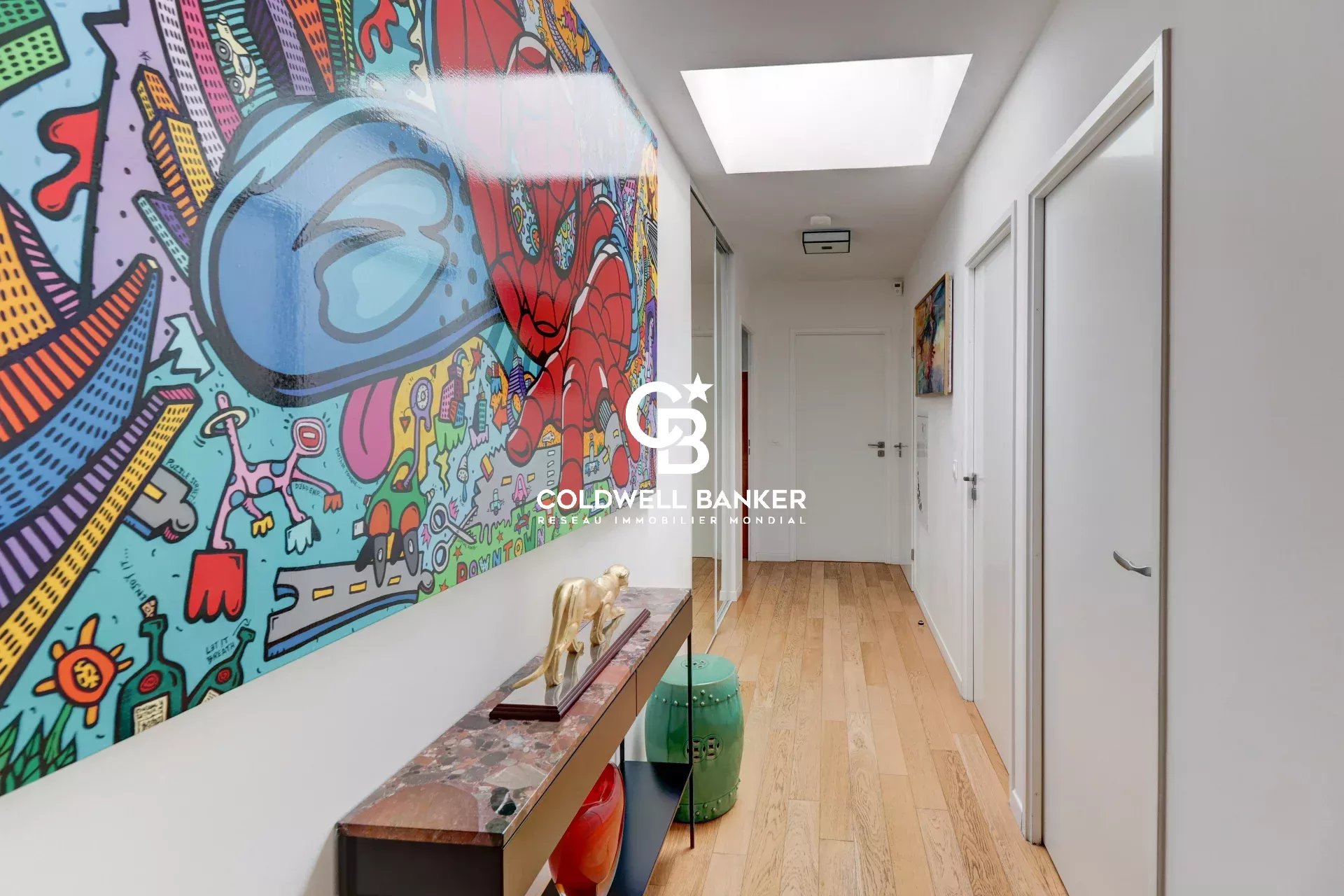 Intérieur d'un appartement moderne avec couloir décoré d'œuvres d'art colorées.