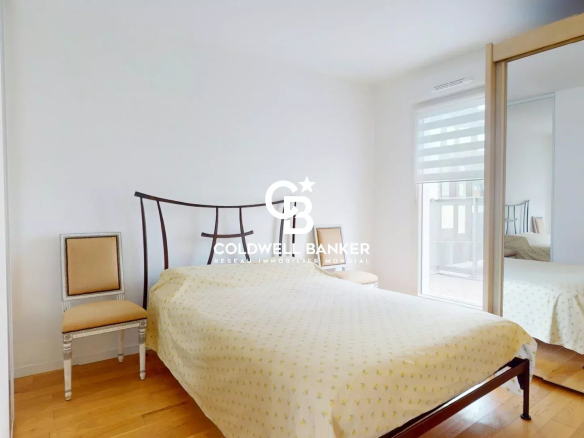 Chambre d'un appartement traversant EST-OUEST à Montrouge, avec un lit et un miroir.