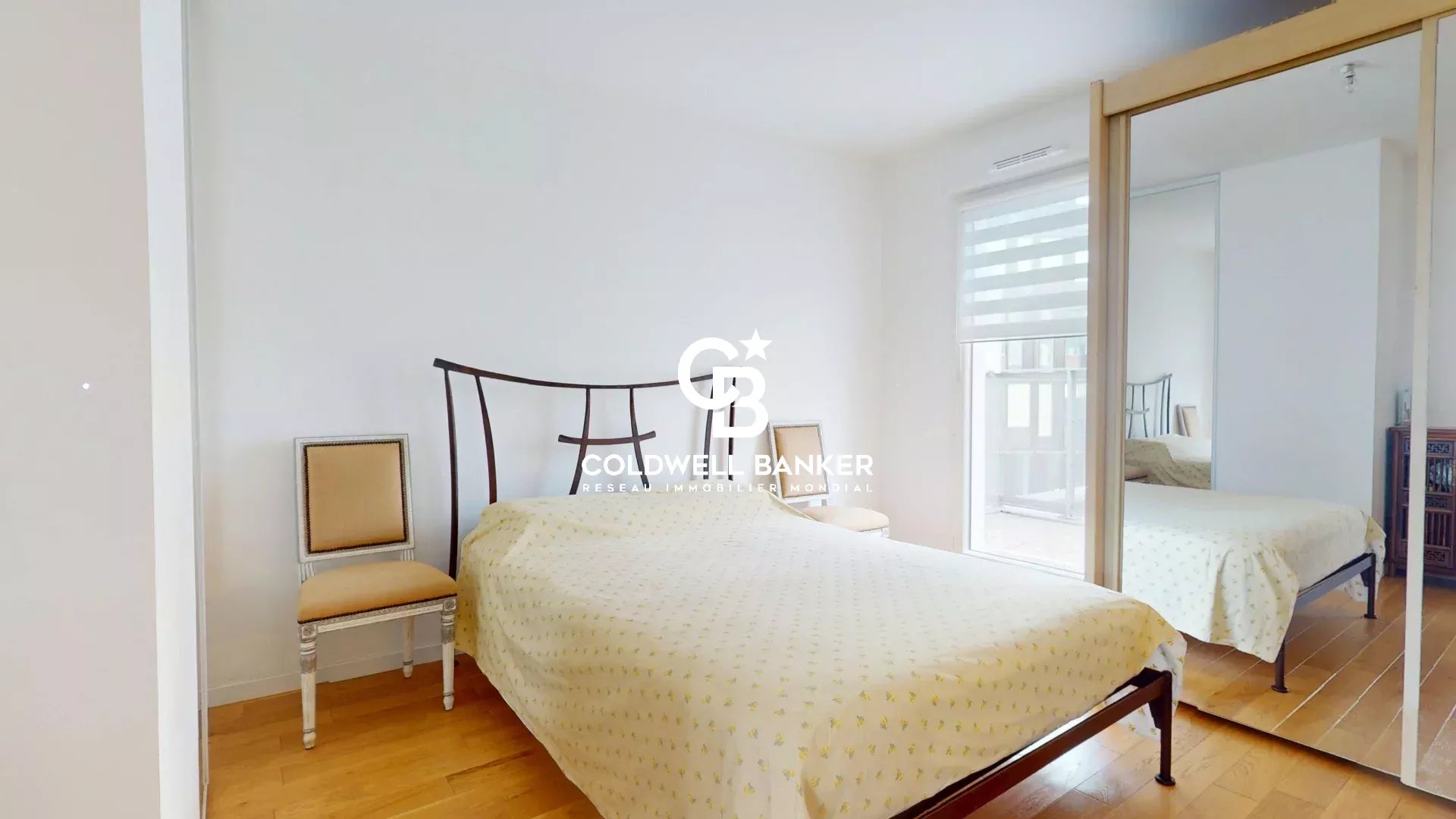 Chambre d'un appartement traversant EST-OUEST à Montrouge, avec un lit et un miroir.