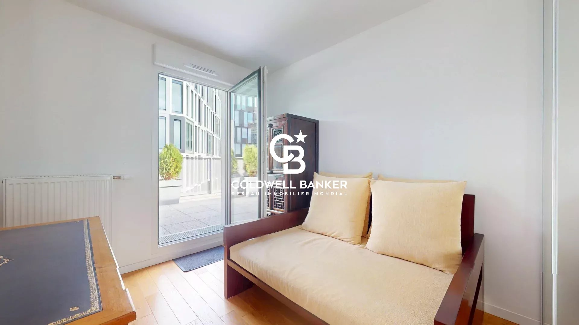 Intérieur d'un appartement lumineux avec un canapé et une porte donnant sur une terrasse.