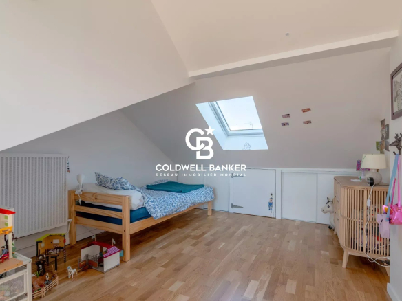 A bedroom in a house with a single bed and toys on the floor, under a sloping roof.