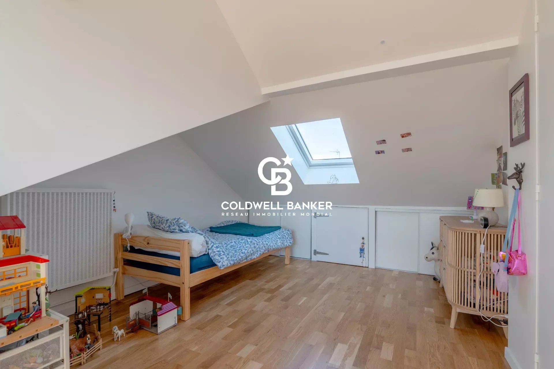 Attic room in a house in Joinville-le-Pont A bedroom in a house with a single bed and toys on the floor, under a sloping roof.