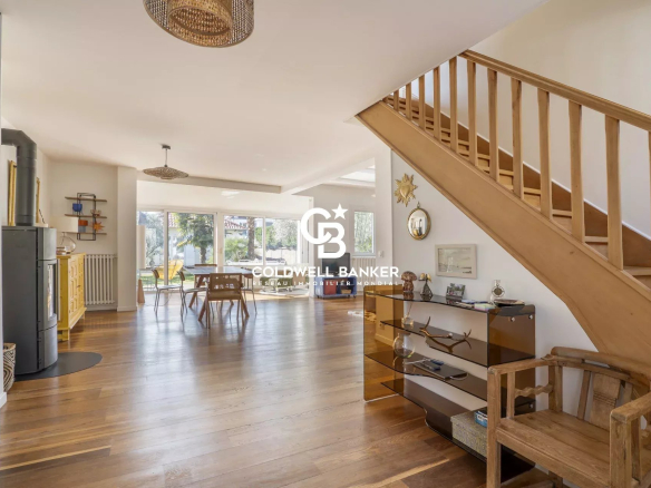 Interior of a modern house with a wooden staircase, a bright living room and a view of the garden.