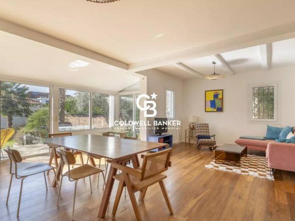 Interior of a spacious house with dining room, living room and large windows.