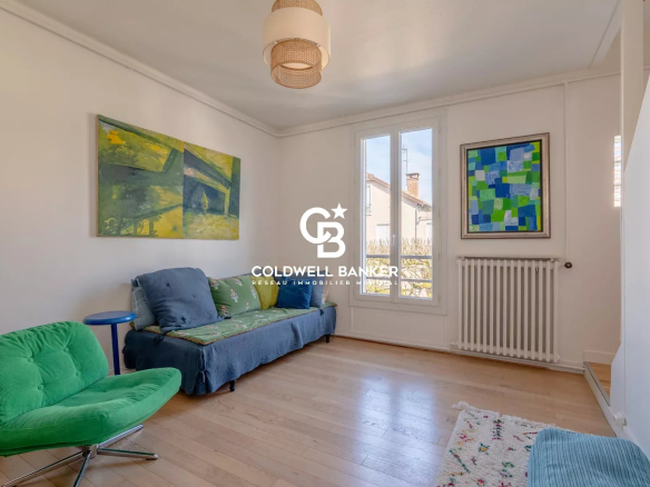 Interior of a house with a bright living room, blue sofa and artwork on the walls.