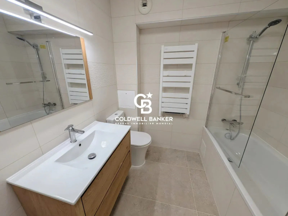 Salle de bain moderne avec baignoire, lavabo et miroir dans un appartement à Issy-les-Moulineaux.