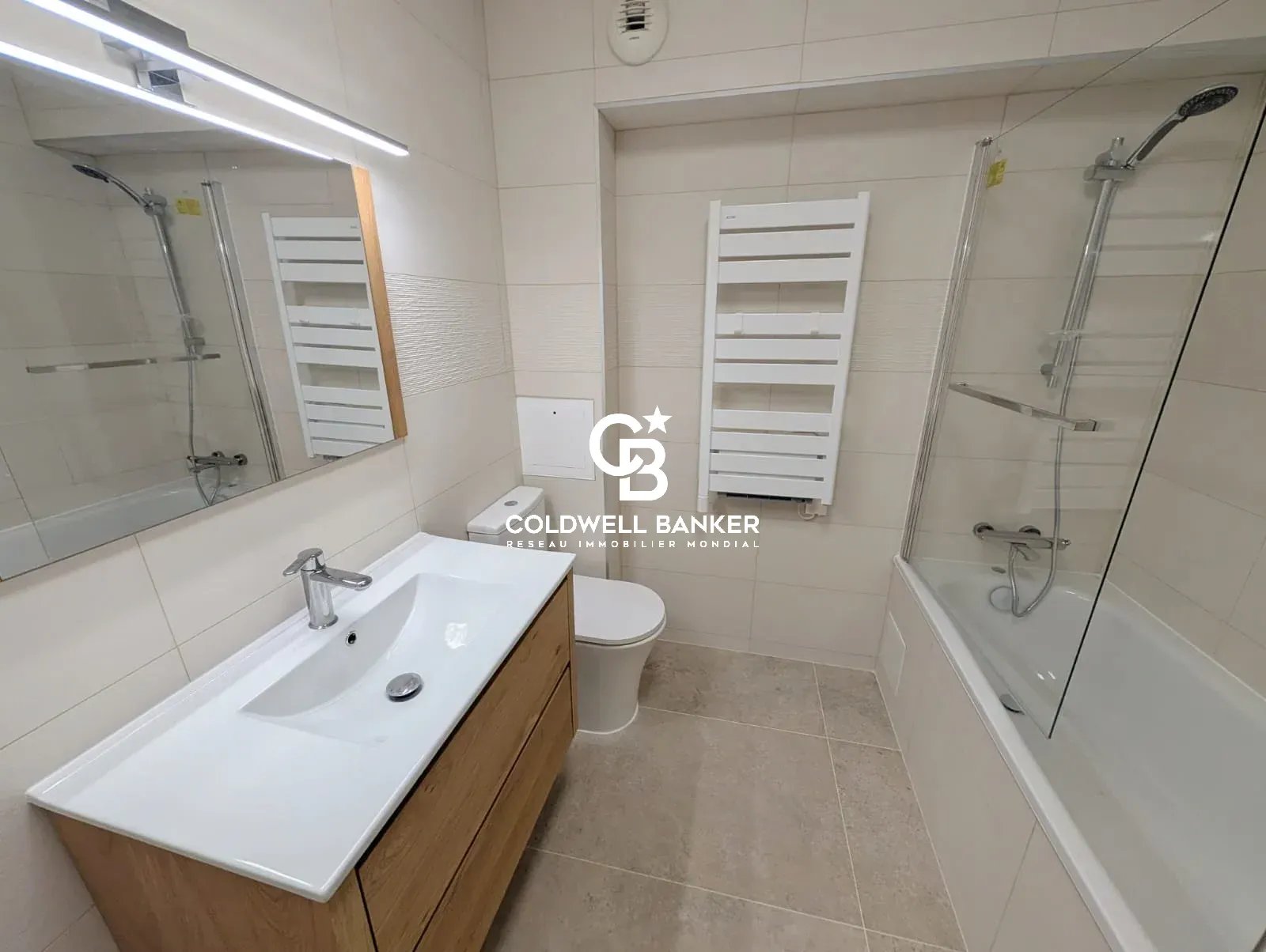 Salle de bain moderne avec baignoire, lavabo et miroir dans un appartement à Issy-les-Moulineaux.