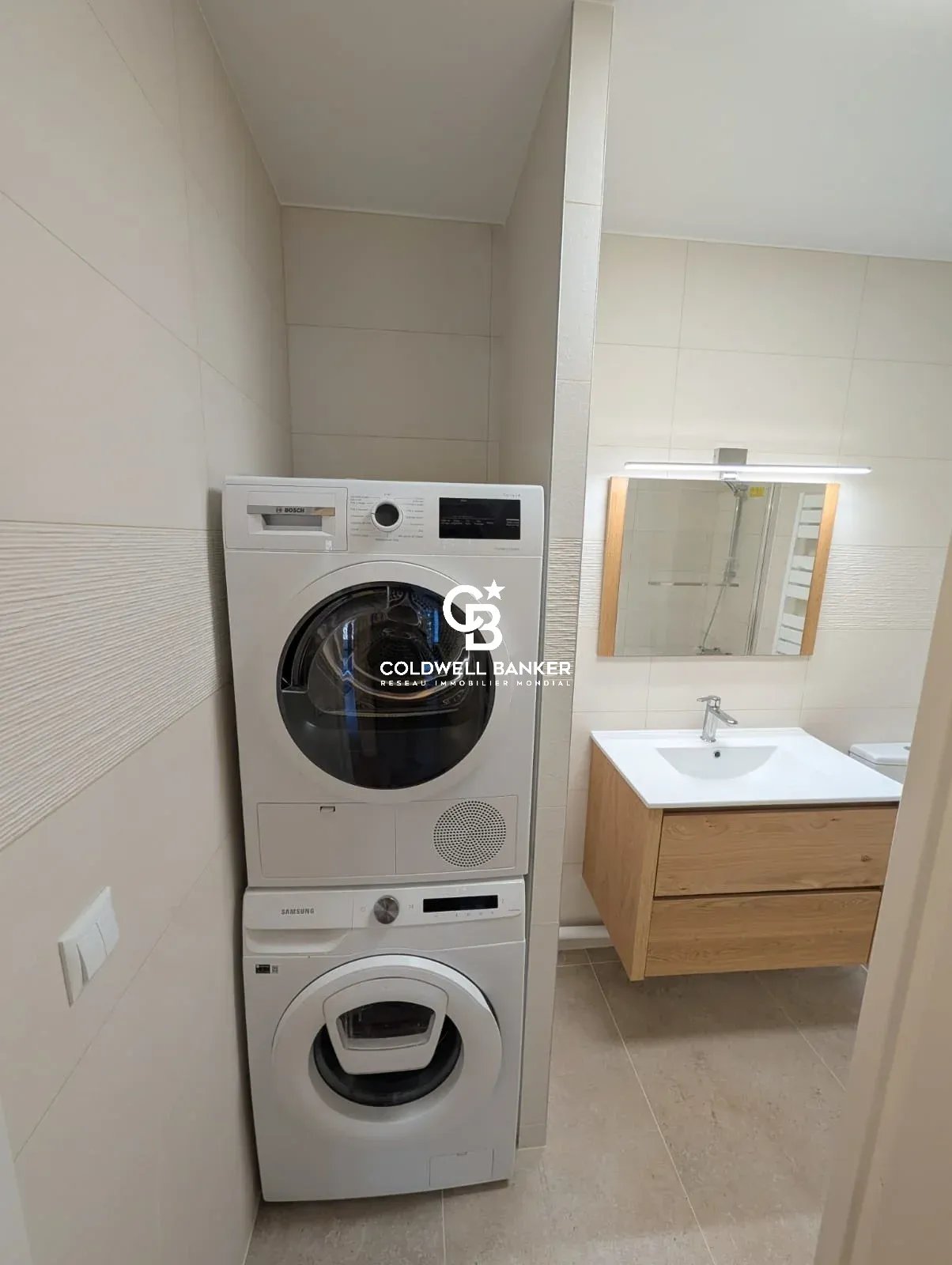 Salle de bain avec machine à laver et sèche-linge intégrés.