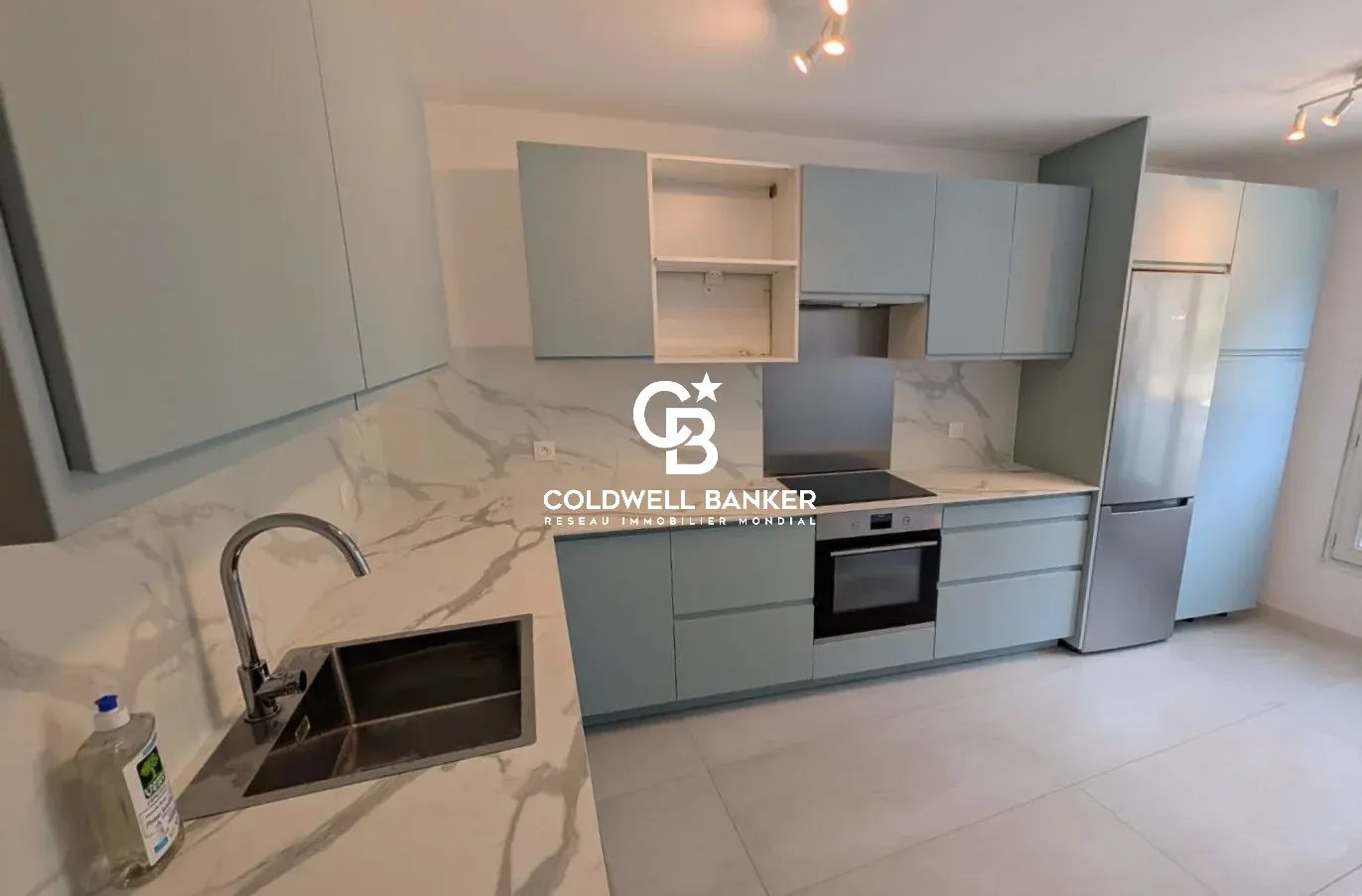 Cuisine moderne d'un appartement à Issy-les-Moulineaux avec meubles en bois clair et plan de travail en marbre.