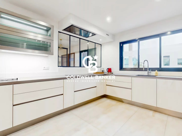 Modern and bright kitchen in a contemporary house in Sceaux, with light-colored furniture and large windows.