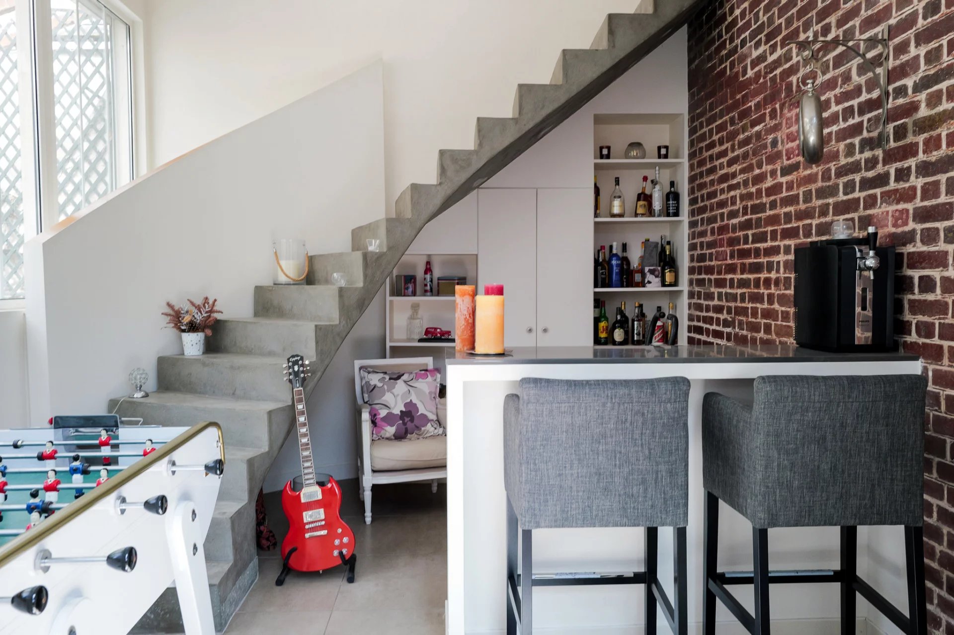 Intérieur d’une maison de caractère Intérieur d'une maison avec un escalier moderne, bar et salon, murs en briques apparentes.
