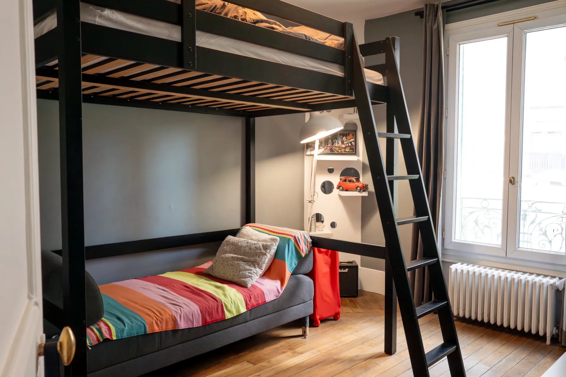 Chambre d’une maison de caractère Chambre avec lit superposé et décoration colorée, fenêtre éclairant l'espace.