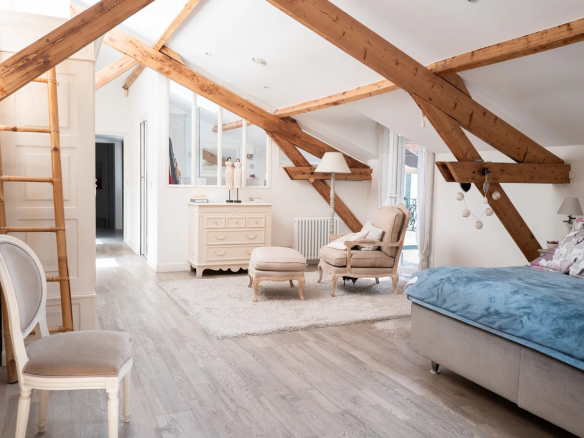Intérieur d'une chambre spacieuse avec poutres apparentes et mobilier élégant.