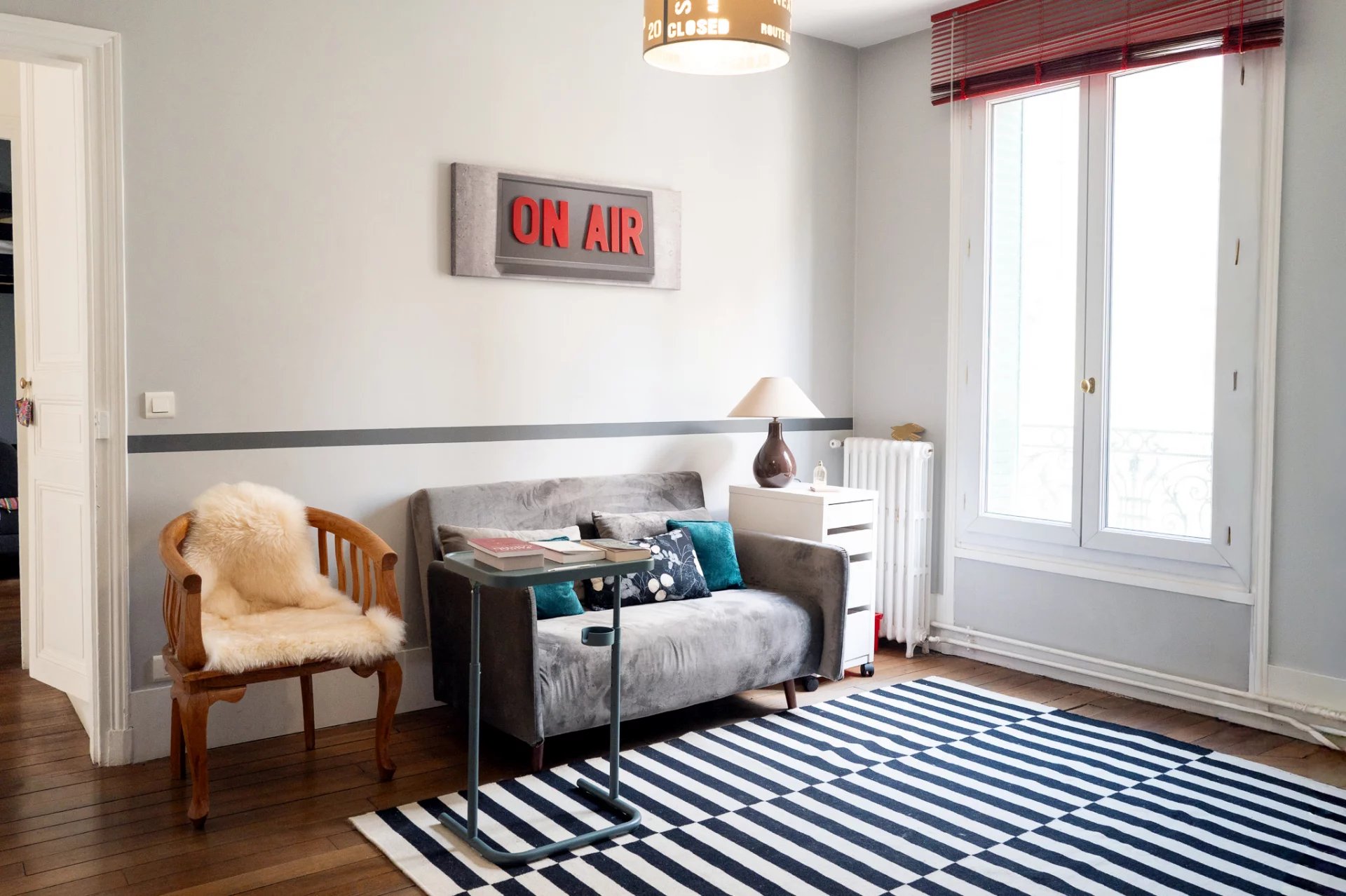 Intérieur d’une maison de caractère Intérieur d'une maison avec un canapé, une chaise en bois et un tapis rayé.