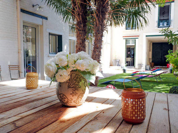 Terrasse d'une maison à Suresnes avec des fleurs blanches et des lanternes, jardin visible en arrière-plan.
