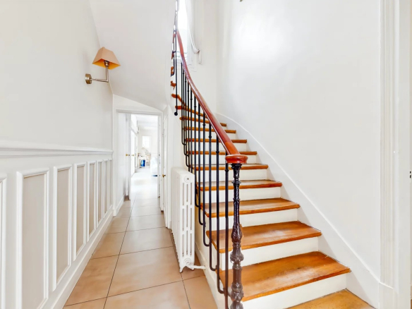 Escalier en bois dans une maison de caractère à Suresnes, avec murs blancs et lumière naturelle.