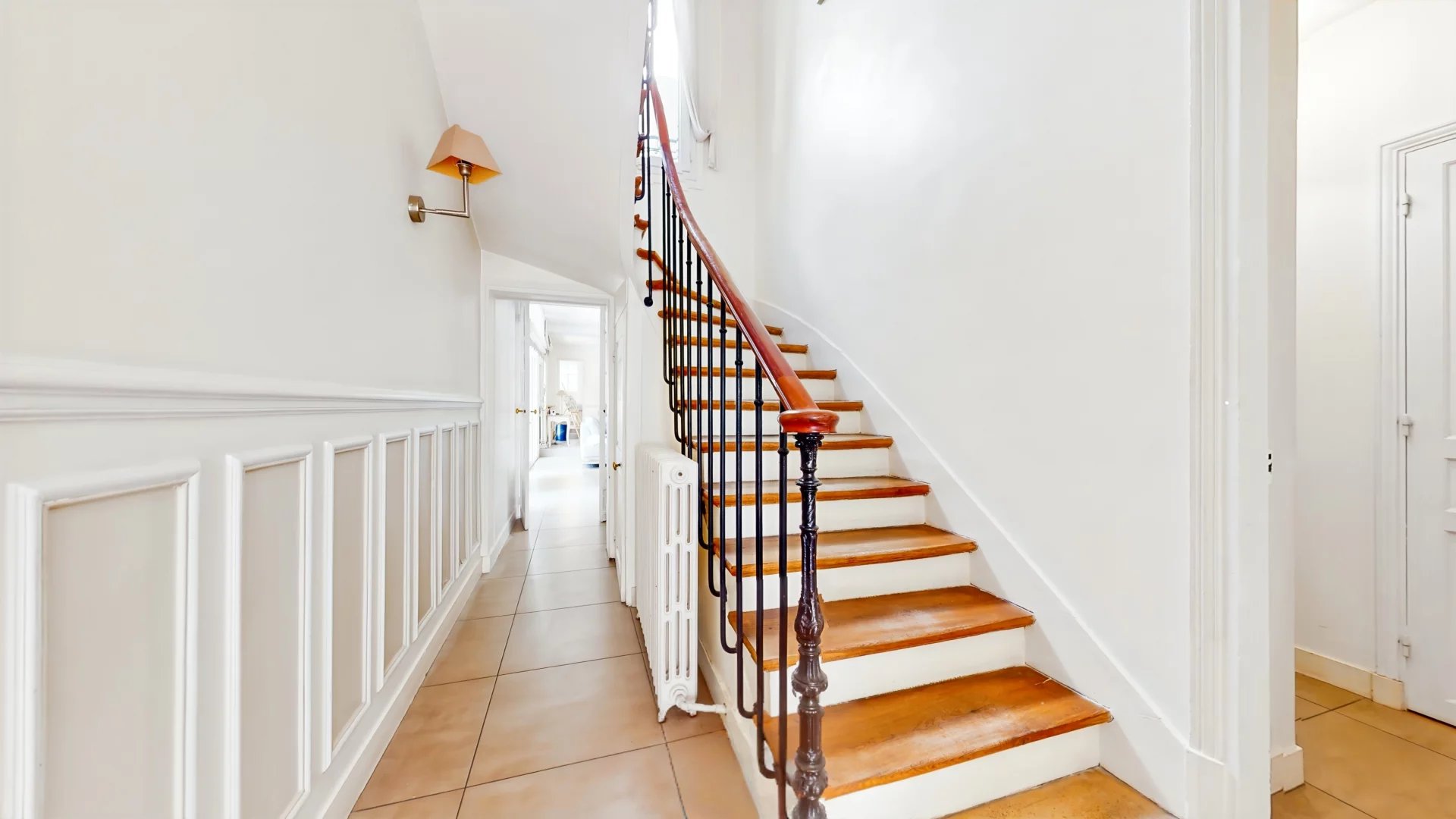 Escalier en bois dans une maison de caractère à Suresnes, avec murs blancs et lumière naturelle.