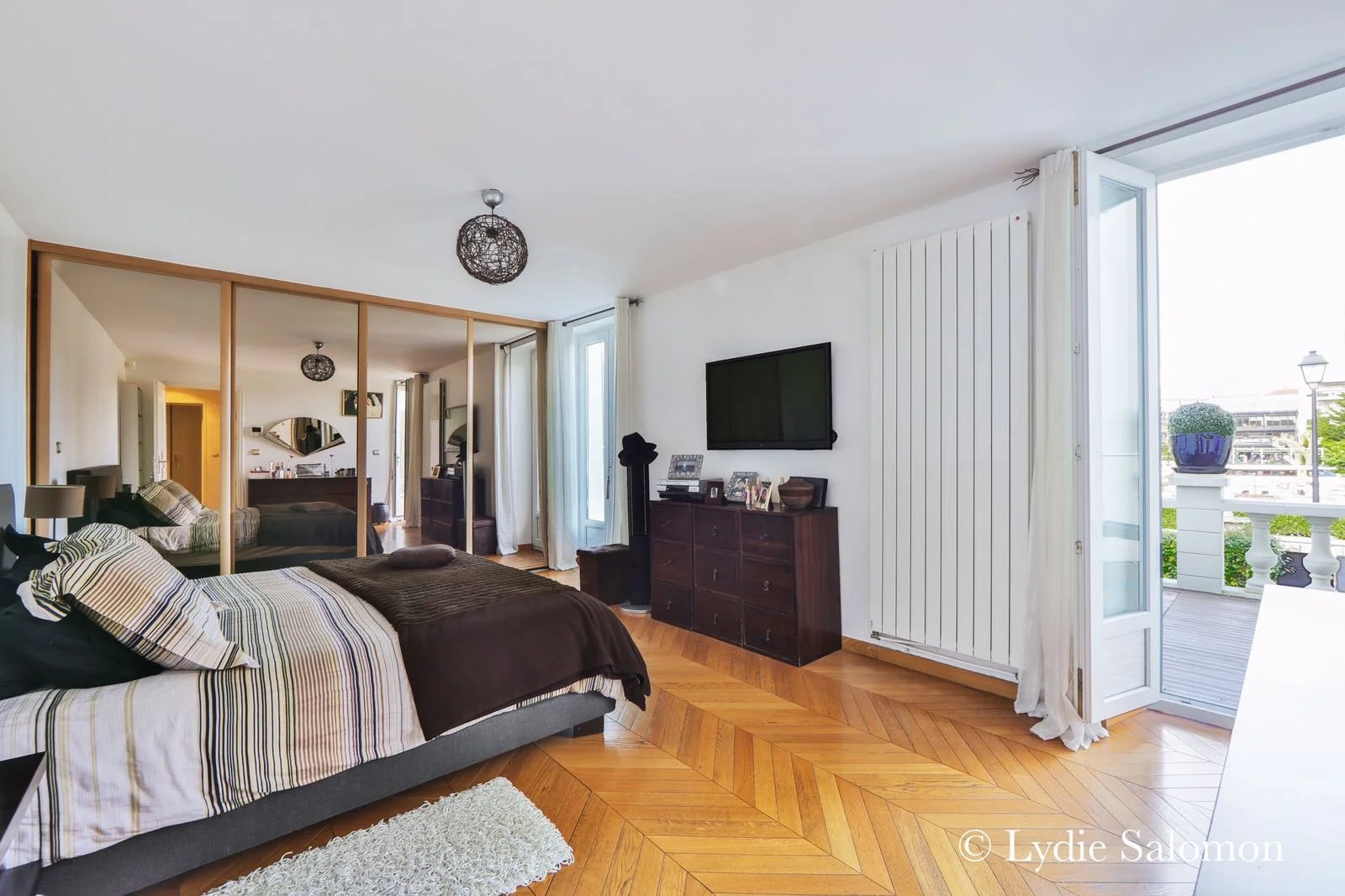 Chambre moderne dans une maison rénovée Chambre d'une maison rénovée avec parquet, télévision et accès à un balcon.