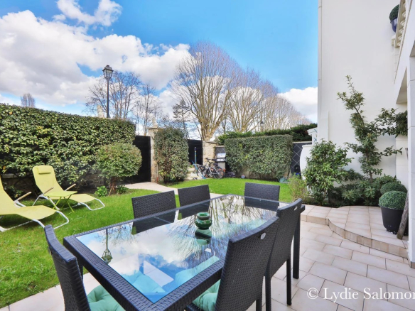 Terrasse avec table et chaises, jardin verdoyant et ciel bleu, maison à Joinville-le-Pont.