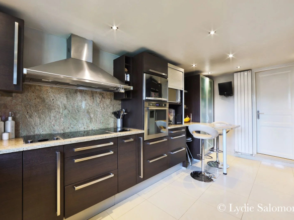 Cuisine moderne et équipée d'une maison rénovée, avec plans de travail en granit et bar à manger.