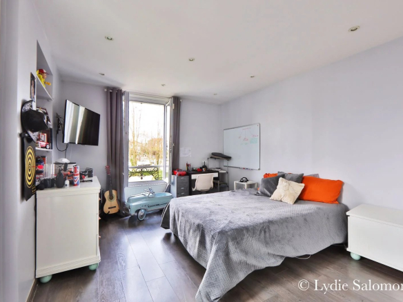 Chambre d'une maison rénovée avec lit, télévision et bureau, à Joinville-le-Pont.
