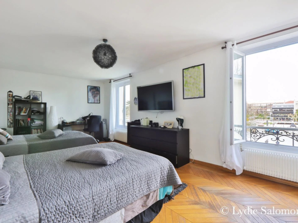 Chambre spacieuse avec deux lits, télévision et fenêtres donnant sur l'extérieur.