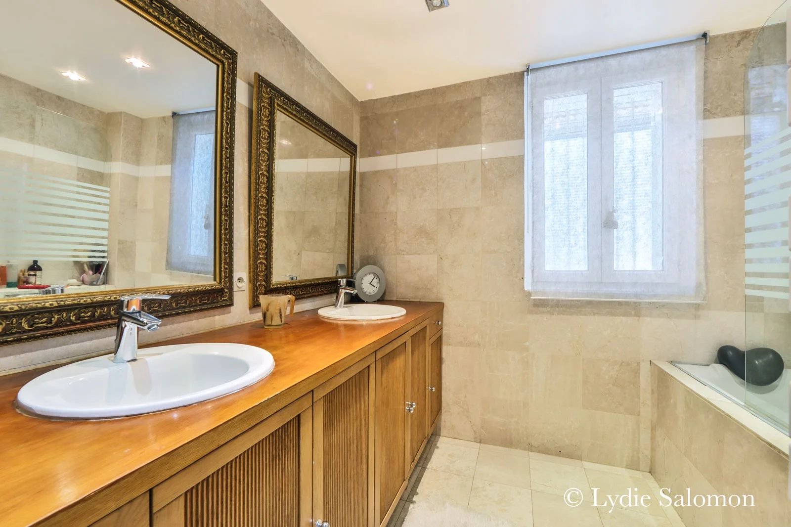 Salle de bain moderne Salle de bain spacieuse avec double vasque et baignoire, murs en pierre beige.