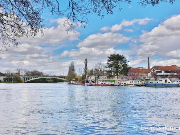 Vue de la Marne avec des bateaux et un pont à Joinville-le-Pont sous un ciel nuageux.