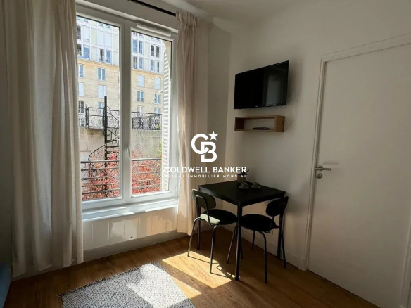 Intérieur d'un studio rénové avec fenêtre, table et chaise, éclairage naturel.